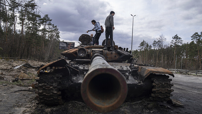 ARCHIV - Anwohner stehen auf einem russischen Panzer, der bei Kämpfen zwischen russischen und ukrainischen Streitkräften in einem Außenbezirken von Kiew beschädigt wurde. Foto: Evgeniy Maloletka/AP/dpa