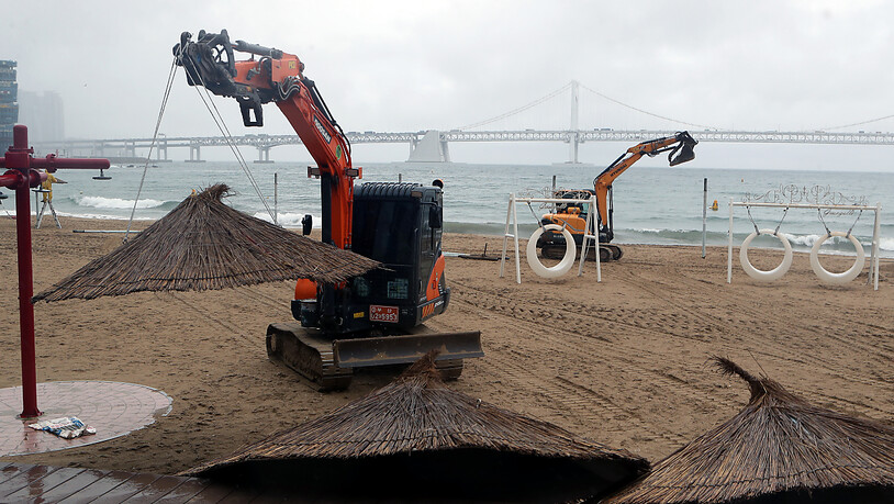 Kran-Bagger bauen am Gwangalli-Strand in Südkorea Sonnenschirme ab, in Vorbereitung auf den Taifun «Hinnamnor». Foto: -/YNA/dpa