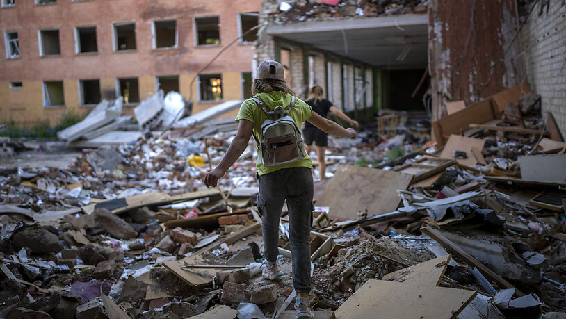 ARCHIV - Die Schülerin Karina Muzyka geht auf den Trümmern der Tschernihiwer Schule Nr. 21, die am 3. März von russischen Streitkräften bombardiert wurde. Foto: Emilio Morenatti/AP/dpa