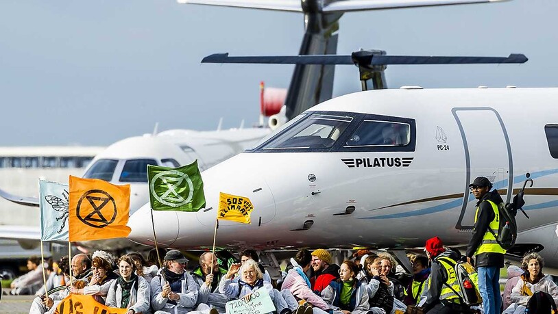Mitglieder verschiedener Umweltvereine führen die Protestaktion "SOS für das Klima" am Flughafen Schiphol durch. Foto: Remko De Waal/ANP/dpa