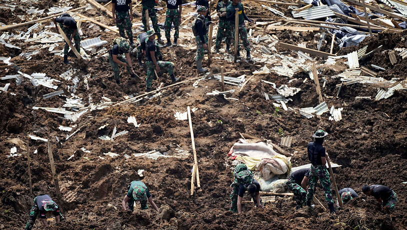 Rettungskräfte suchen nach Opfern eines durch ein Erdbeben ausgelösten Erdrutsches. Foto: Tatan Syuflana/AP/dpa