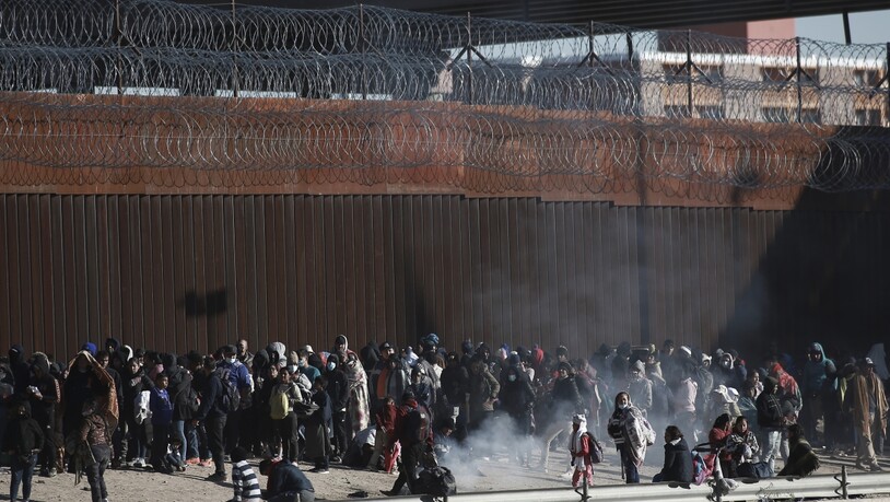 Migranten aus Lateinamerika stehen an der Grenzmauer zwischen Mexiko und den USA. Foto: Christian Chavez/AP/dpa