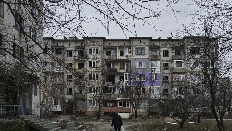 Ein Zivilist geht in Soledar an schwer beschädigten Wohngebäuden vorbei. Angehörige der berüchtigten russischen Söldnertruppe Wagner haben die Eroberung des Ortes verkündet. Foto: Libkos/AP/dpa
