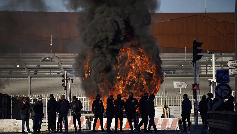 Hafenarbeiter vor einer brennenden Barrikade in von Marseille. Foto: Daniel Cole/AP/dpa