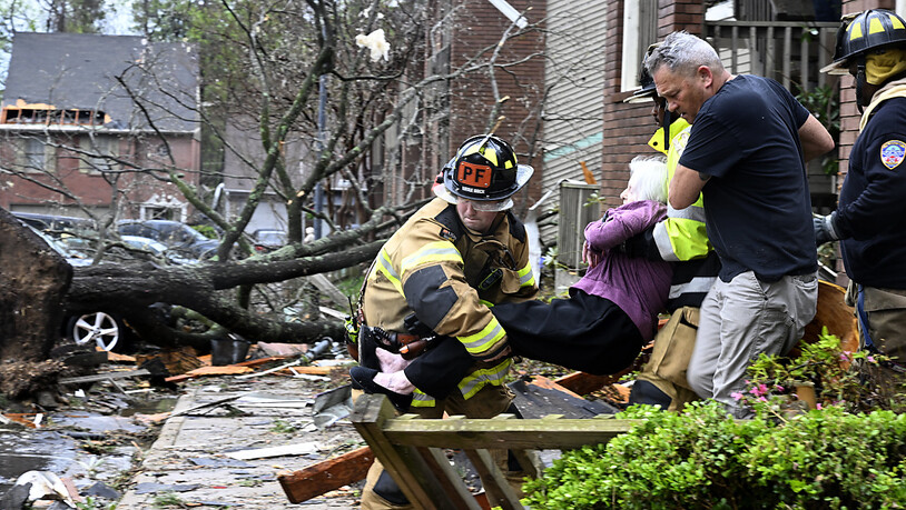 Feuerwehrleute tragen eine Frau aus ihrer Wohnung, nachdem ihr Gebäudekomplex durch einen Tornado beschädigt wurde. Foto: Stephen Swofford/Arkansas Democrat-Gazette/AP/dpa - ACHTUNG: Nur zur redaktionellen Verwendung und nur mit vollständiger Nennung des…