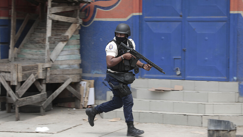 ARCHIV - Ein Polizeibeamter geht während einer Anti-Gang-Operation im Stadtteil Portail in Deckung, einen Tag nachdem eine aufgebrachte Menschenmenge hat in Haitis Hauptstadt Port-au-Prince mehr als zehn mutmaßliche Bandenmitglieder getötet. Foto: Odelyn…