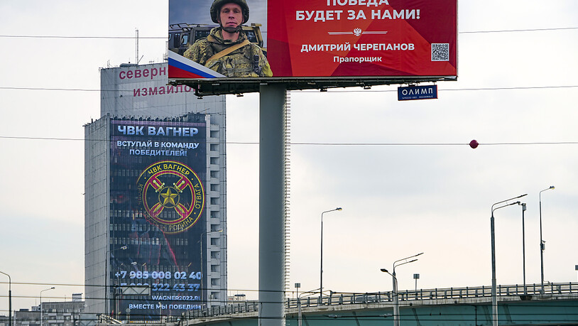 ARCHIV - An der Fassade eines Gebäudes ist ein Werbeschild zu sehen, auf dem für das Militärunternehmen Wagner (hinten) geworben wird und auf dem zu lesen ist «Schließen Sie sich dem Team der Sieger an». Foto: Alexander Zemlianichenko/AP/dpa