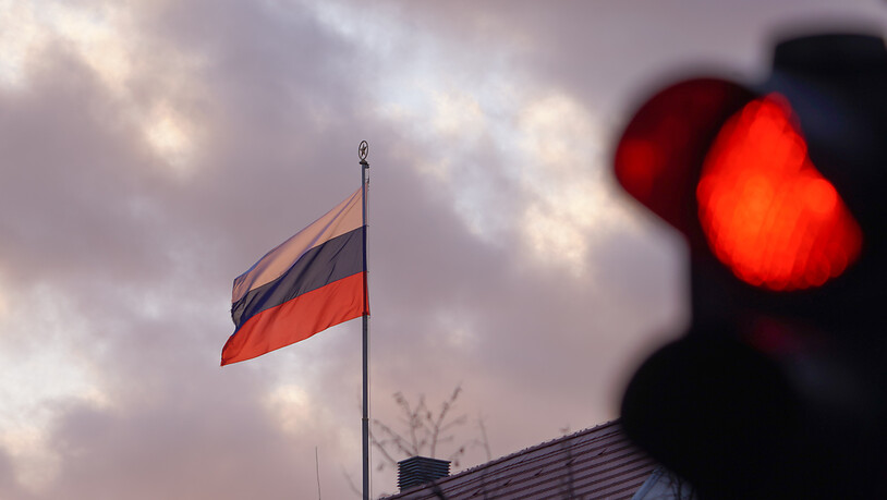 ARCHIV - Die Flagge der Russischen Botschaft weht am frühen Morgen hinter einer roten Ampel. Als Reaktion auf die Ausweisung von deutschen Staatsbediensteten hat die Bundesregierung Russland den Betrieb von vier Generalkonsulaten in Deutschland untersagt…