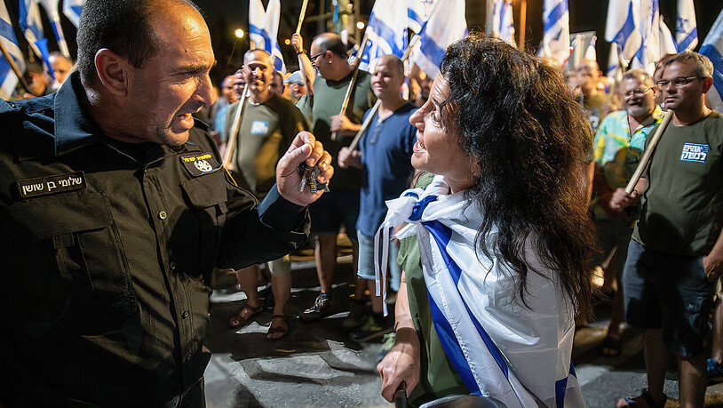 Eine Demonstrantin diskutiert vor einer Polizeistation mit einem Polizeibeamten während einer Demonstration gegen die Justizreform. Foto: Matan Golan/SOPA Images via ZUMA Press Wire/dpa
