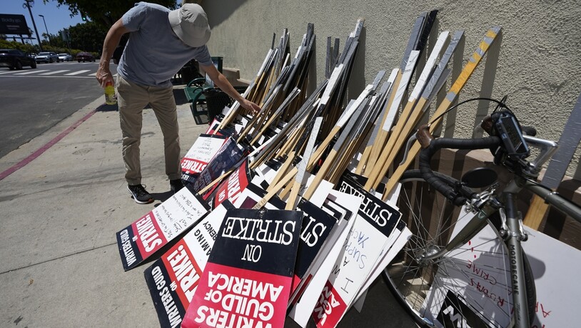 Ein Demonstrant wählt während einer Kundgebung der Writers Guild ein Protest-Schild aus. Schauspielerinnen und Schauspieler in den USA treten in den Streik. Foto: Mark J. Terrill/AP