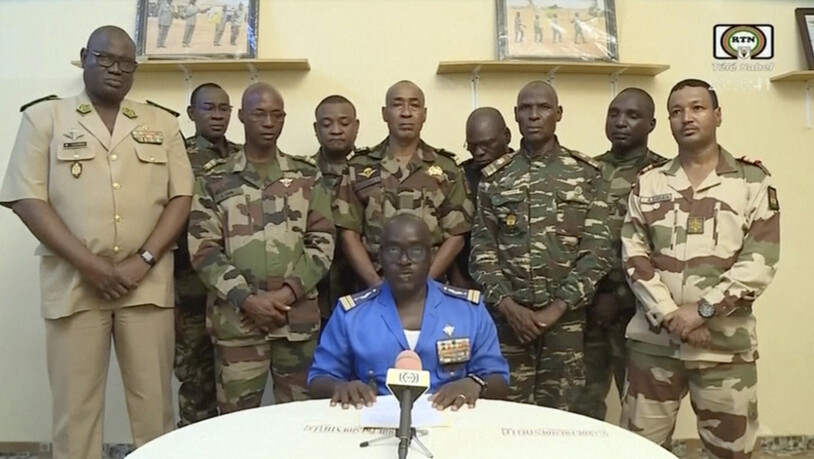 dpatopbilder - HANDOUT - Eine Delegation von Militäroffizieren steht hinter Oberstmajor Amadou Abdramane (vorne, M), der im nigrischen Staatsfernsehen eine Reihe von Kommuniqués verliest, in denen ein Staatsstreich angekündigt wird. Foto: Uncredited/ORTN…