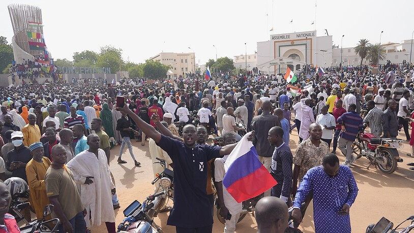 Ein Teilnehmer des Marsches in Niamey im Niger, zu dem Anhänger des Putschisten General Omar Tchiani aufgerufen haben, hält eine russische Flage in der Hand. Foto: Sam Mednick/AP/dpa