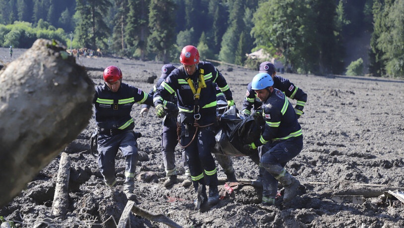 HANDOUT - Rettungskräfte tragen die Leiche des Opfers eines Erdrutsches in der Nähe von Schowi. Infolge eines Erdrutsches sind in einem Ferienort in Georgien im Kaukasusgebirge offiziellen Angaben zufolge mindestens elf Menschen ums Leben gekommen. Foto:…