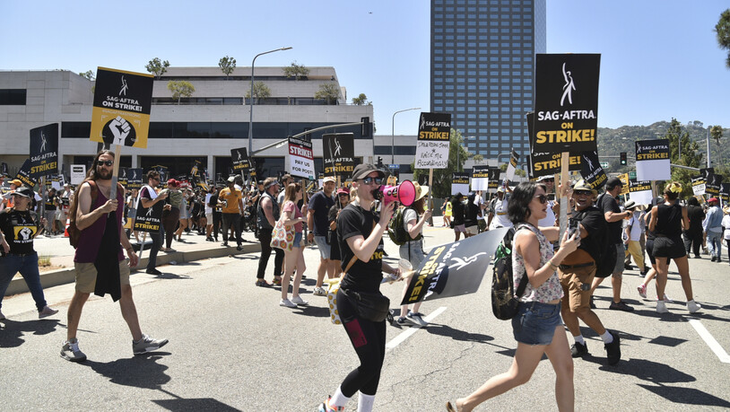 Personen halten Schilder an der Streikpostenkette vor den Universal Studios in Universal City. Der Streik der Schauspieler findet mehr als zwei Monate nach dem Streik der Drehbuchautoren statt, die sich für bessere Bezahlung und Arbeitsbedingungen…