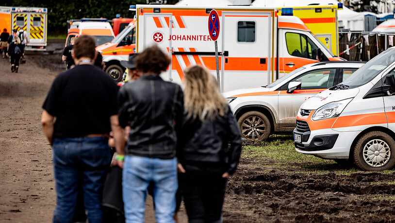 Festivalbesucher stehen vor dem im Schlamm stehenden Fuhrpark an Rettungsfahrzeugen. Foto: Axel Heimken/dpa