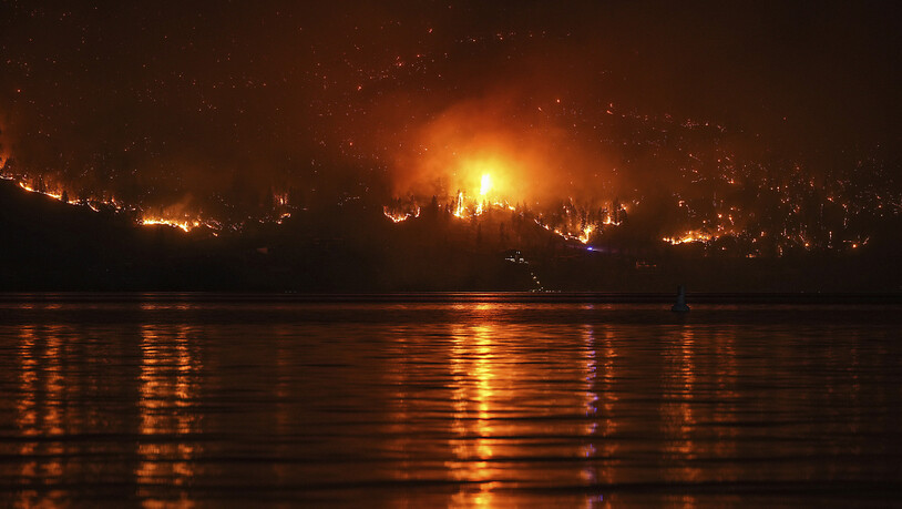 Ein Waldbrand am McDougall Creek an einem Berghang oberhalb eines Hauses am Seeufer. Foto: Darryl Dyck/The Canadian Press/AP/dpa