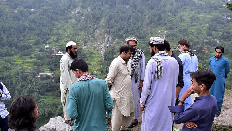 Anwohner und Journalisten versammeln sich in der Nähe des Unglücksortes in Pakistan. Foto: Saqib Manzoor/AP/dpa