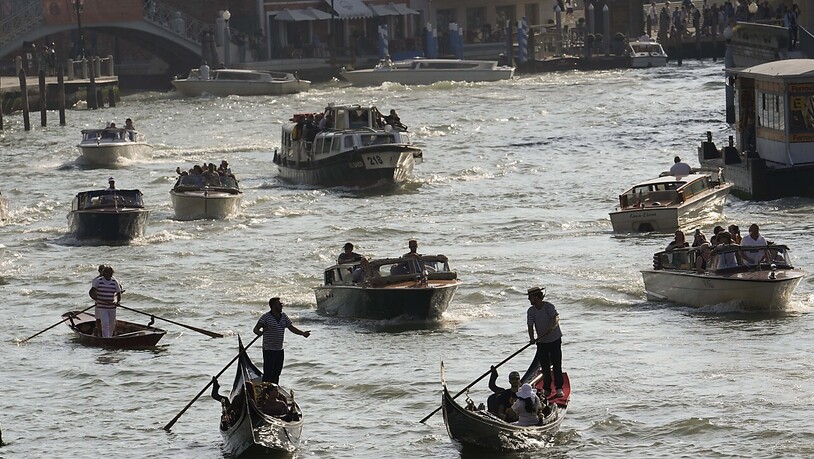 Boote und Gondeln fahren auf einem Kanal. Die UN-Kulturorganisation Unesco hat beschlossen, Venedig und seine Lagune - anders als beabsichtigt - nicht in die Liste des gefährdeten Welterbes aufzunehmen. Foto: Luca Bruno/AP/dpa