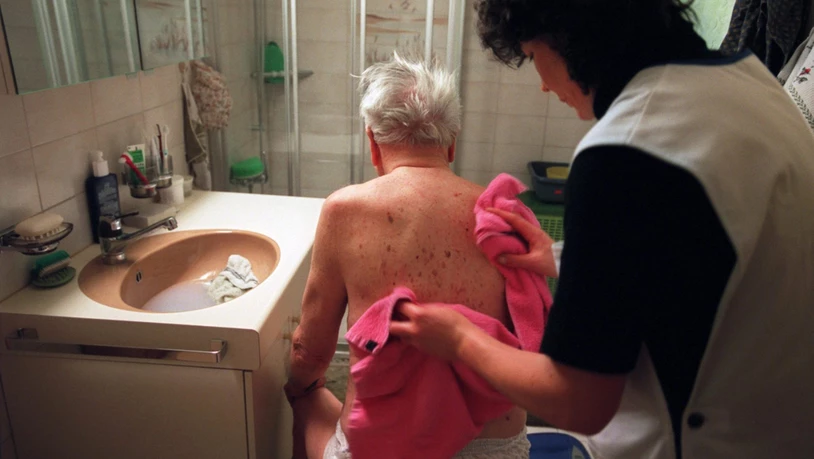 Eine Angestellte der Spitex wäscht den Rücken eines betagten Mannes.
