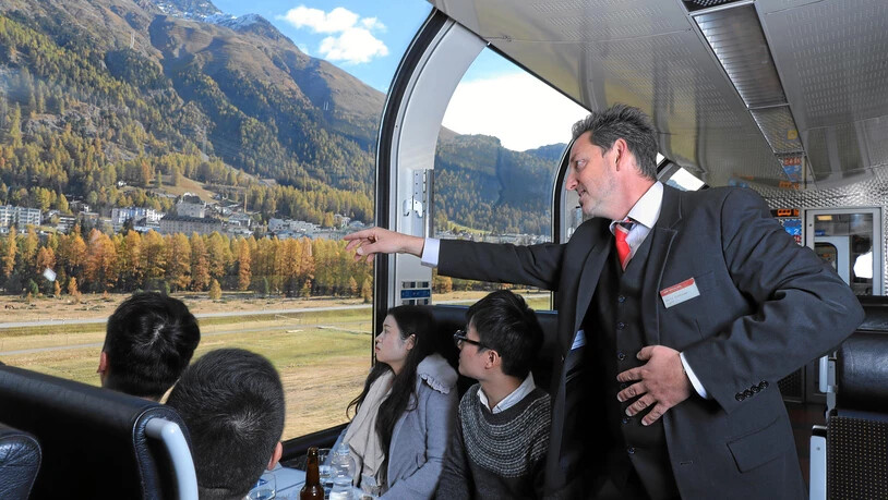 Ein Zugbegleiter erklärt Fahrgästen im Bernina Express die Landschaft. Pressebild