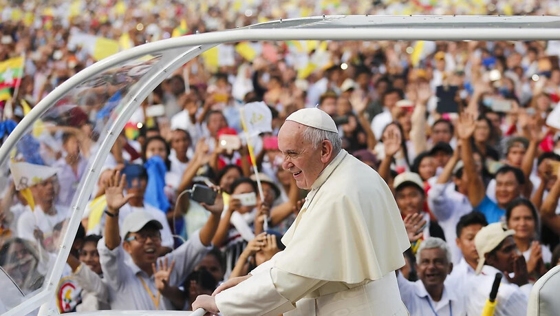 Papst Franziskus winkt am Mittwoch in Rangun vom Papamobil aus den zahlreichen Gläubigen zu.