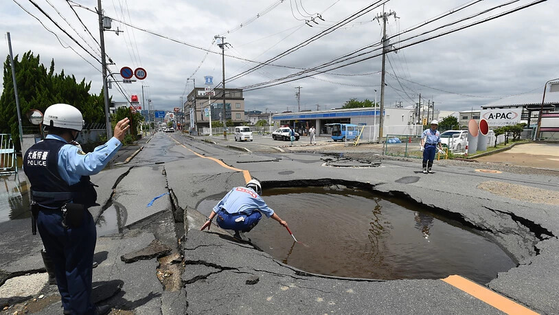 Arbeiter checken die Schäden durch ein Erdbeben an einer Strasse.