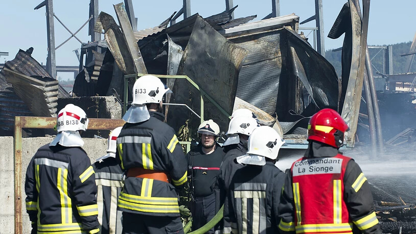 Feuerwehrleute überwachen am Donnerstag die Brandstätte auf dem Gelände der Sägerei Despond, die dem Freiburger SVP-Nationalrat Jean-François Rime gehört.