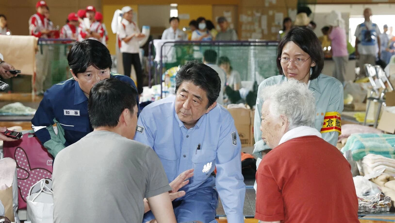 Japans Regierungschef Shinzo Abe (Mitte) spricht den Betroffenen der Unwetterkatastrophe Mut zu.