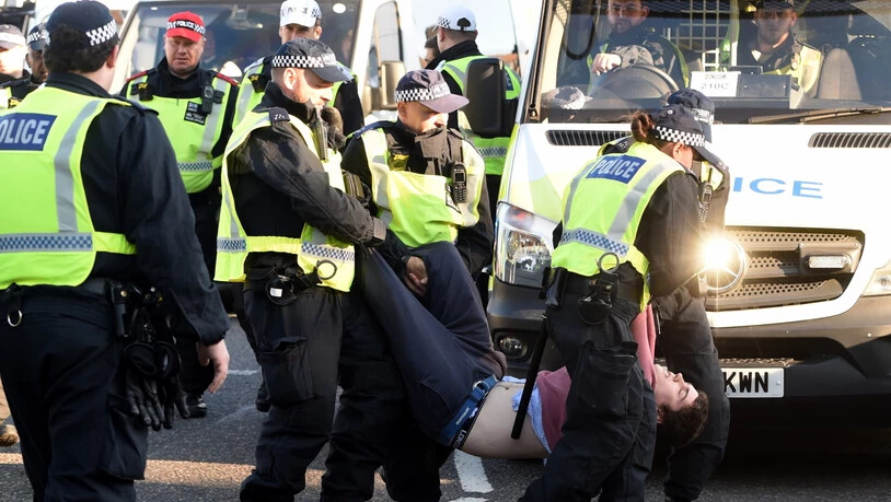 Ein Demonstrant wird von der Polizei von der Lambeth Bridge weggetragen.