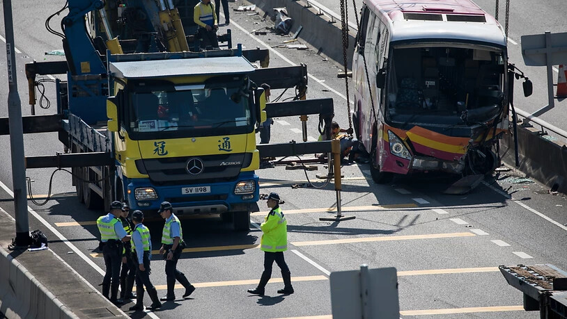 Nach der tödlichen Kollision zwischen einem Bus und einem Taxi in Hongkong räumen Arbeiter das Buswrack von der Autobahn.