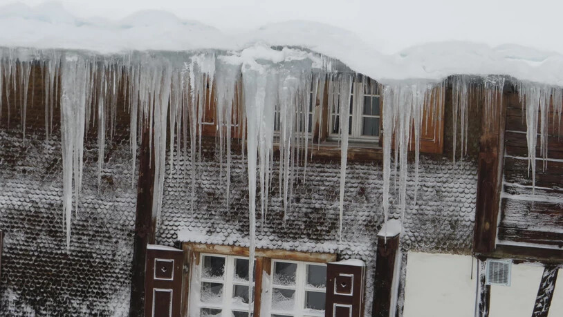 Lange Eiszapfen hängen von den Hausdächern.