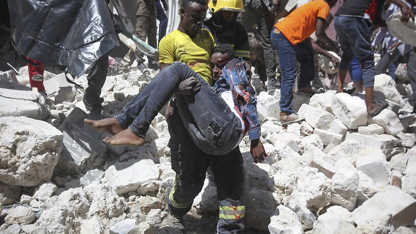 Nach der Explosion einer Autobombe vor einem Einkaufszentrum in Mogadischu trägt ein Feuerwehrmann einen Verletzten weg vom Anschlagsort.