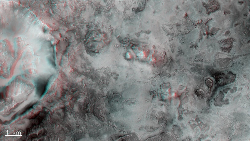 Ein Krater und unebenes Terrain zwischen den Syrtis und
Isidis-Regionen des Mars. Das Bild kann mit
einer rot-blauen Stereobrille betrachtet werden, um
einen Eindruck der Tiefe zu erhalten.