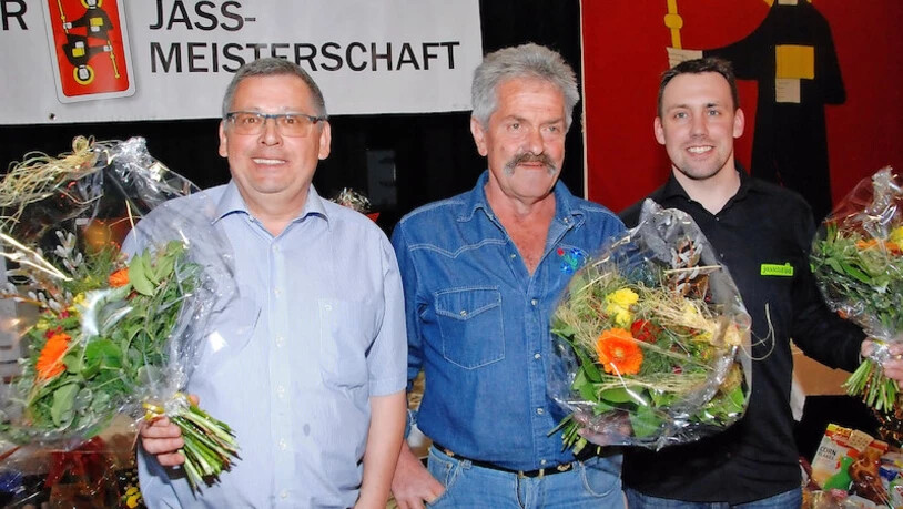 Renato Pesaballe (von links; 2. Rang), Kaspar Trümpi (1. Rang und Jasskönig 2019) und Thomas Allenspach (3. Rang) freuen sich mit Blumen beschenkt über ihren Erfolg in der 13. Glarner Jass-Meisterschaft.
