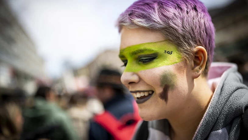Farbe und ein Lächeln müssen auch sein: Junge Frau an der Klimademo in Lausanne.