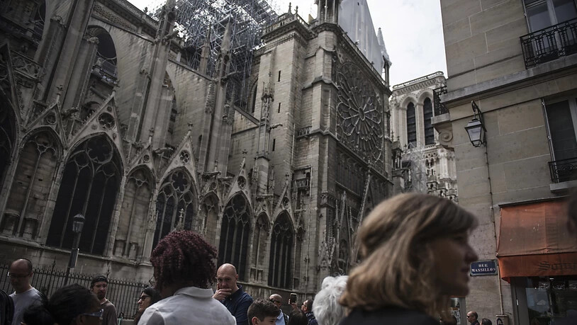 Touristen sehen sich gut eine Woche nach dem verheerenden Brand den Schaden an der Kathedrale Notre-Dame an.  Am Dienstag wurde begonnen, eine Plane auf der mehr als 850 Jahre alten Kathedrale anzubringen, deren Dach in grossen Teilen zerstört wurde. …