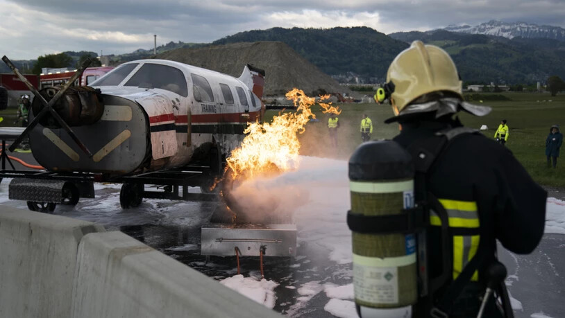 Ein Kleinflugzeug brennt, ein Feuerwehrmann greift ein: Notfallübung auf dem Flugplatz in Thun.