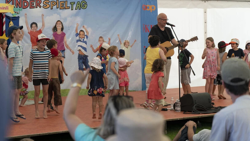 Bruno Hächler bringt mit Gitarre und Kinderliedern Stimmung auf der Bühne.