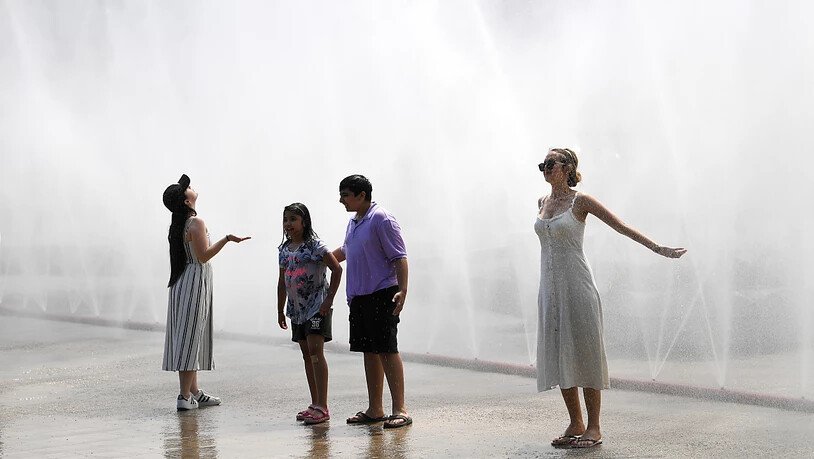 Touristen kühlen sich an einem Sprühregen aus einem Wasserschlauch in Wien.(Themenbild)