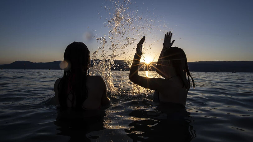 Glücklich, wer ins Wasser kann: Zwei Mädchen nehmen ein erfrischenden Bad bei Sonnenuntergang im Neuenburgersee. (Archivbild)