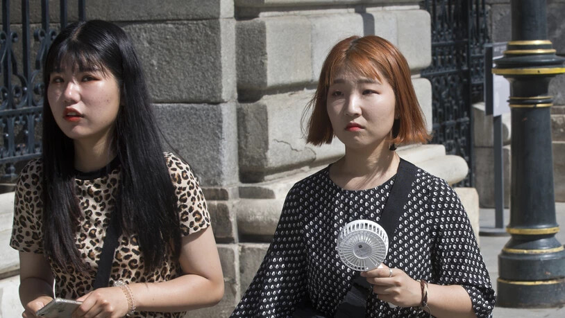 Asiatische Touristinnen mit protablem Ventilator unterwegs in der spanischen Hauptstadt Madrid.