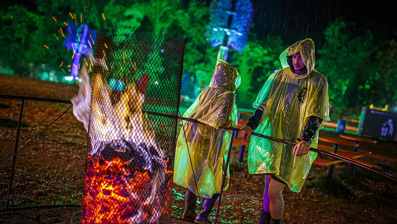 Das 44. Paléo Festival in Nyon ging am Sonntag zu Ende: Auch der Regen konnten dem Openair nichts anhaben. Besucher in Regenpellerinen stehen an einer Feuerstelle.