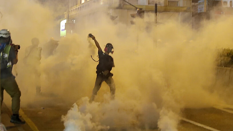 Ein Demonstrant in Hongkong wirft einen Tränengaskanister zurück.