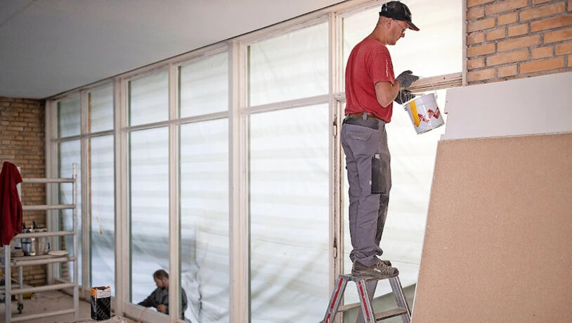 Nicht reflektierendes Glas: Handwerker füllen Fugen der neuen Fenster des Foyers.