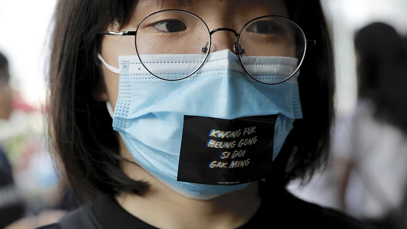 Eine Frau trägt während einer Anti-Regierungs-Demonstration in Hongkong eine Maske mit der Aufschrift "Fügt Öl hinzu, Leute aus Hongkong".