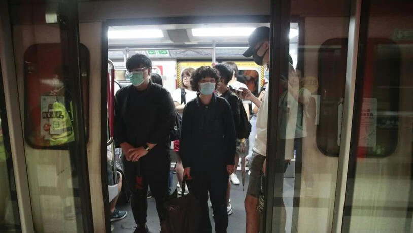 Schwarzgekleidete Demonstranten blockieren im morgendlichen Berufsverkehr in Hongkong die Türen zahlreicher U-Bahnen und halten sie so von der Weiterfahrt ab.
