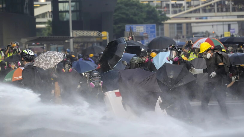 Demonstranten schützen sich mit Schirmen vor den Wasserkanonen.