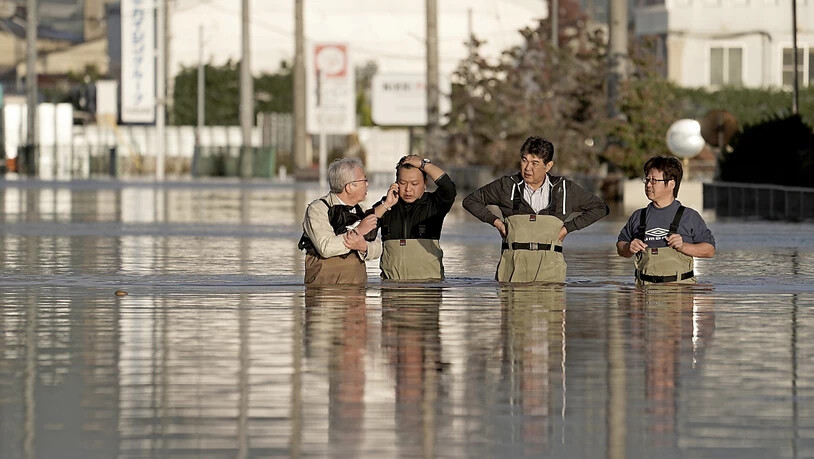 In Nagano stehen Angestellte einer Firma im Hochwasser, um den Zustand ihres Büros (nicht im Bild) zu prüfen. Die Provinz Nagano war am stärksten von Überschwemmungen betroffen, nachdem der Chikuma-Fluss durch die Uferdämme gebrochen war.