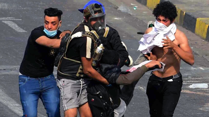 Demonstranten bringen in Bagdad einen Verletzten in Sicherheit.