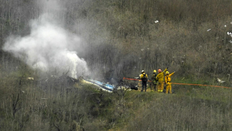 Feuerwehrleute löschen den abgestürzten Helikopter.